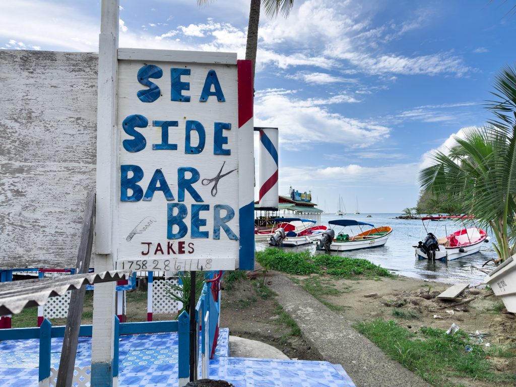 Hand painted rustic Sea Side Barber sign with fishing boats in background, Marigot Bay, St. Lucia