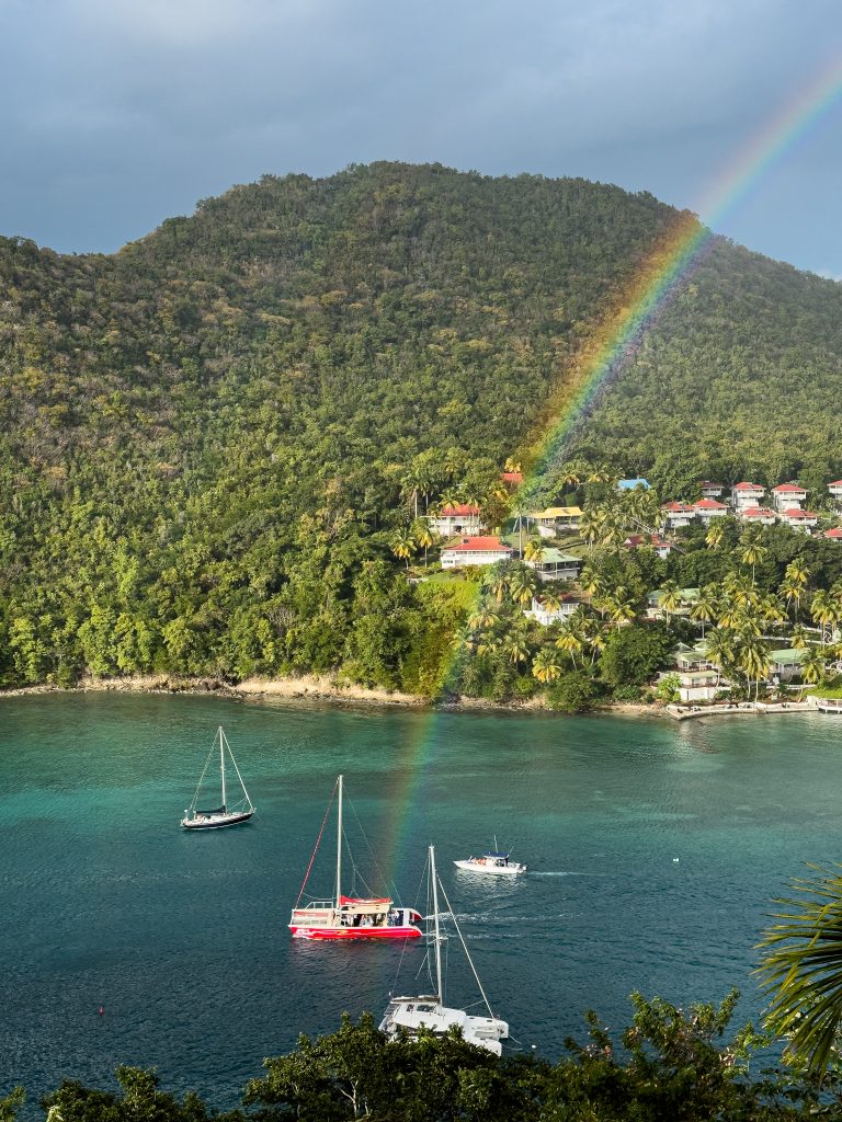 Rainbow shooting out of red catamaran sailboat in Marigot Bay, St. Lucia